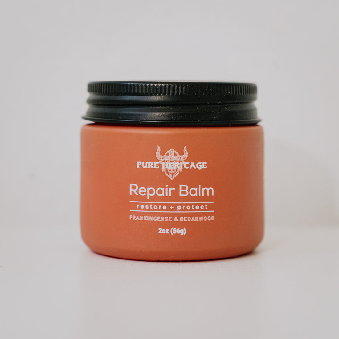 Orange jar of Pure Heritage Repair Balm with black lid on a light gray background