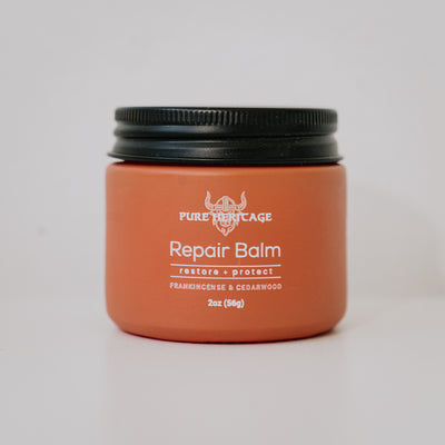 Orange jar of Pure Heritage Repair Balm with black lid on a light gray background