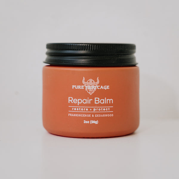 Orange jar of Pure Heritage Repair Balm with black lid on a light gray background